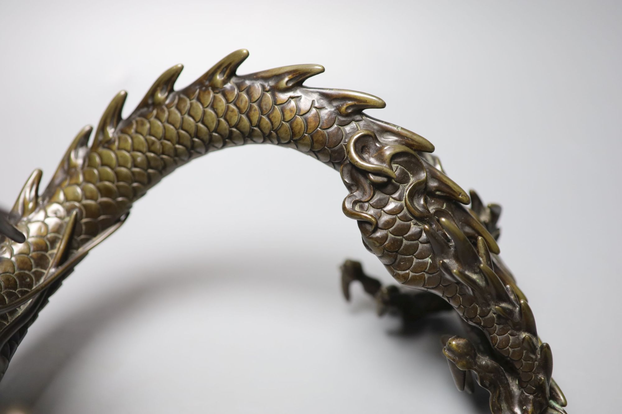 A large Japanese bronze model of a dragon clasping a glass jewel, 29.5cm across